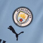 Camiseta Manchester City Primera Equipación 2022-2023 Versión Fan escudo