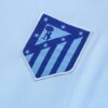 Escudo del chándal celeste del Atlético de Madrid 2022-2023