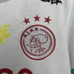 Camiseta Ajax 2025-2026 Edición Especial Bob Marley 40 Aniversario-escudo 1