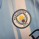 conjunto-niño-manchester-city-primera-equipacion-2025-2026-escudo